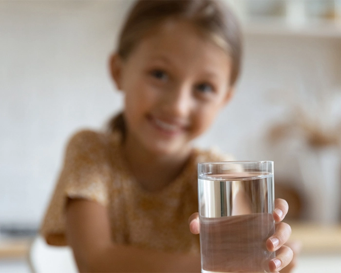 Trinken in der Kita Mädchen mit einem Glas Wasser in der Hand