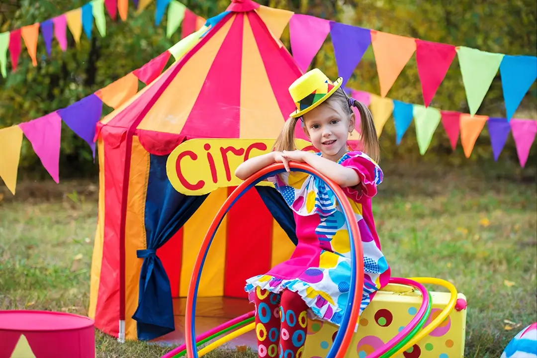 Kita-Projekte zum Thema Zirkus: Mädchen verkleidet vor einem Kinder-Zirkuszelt