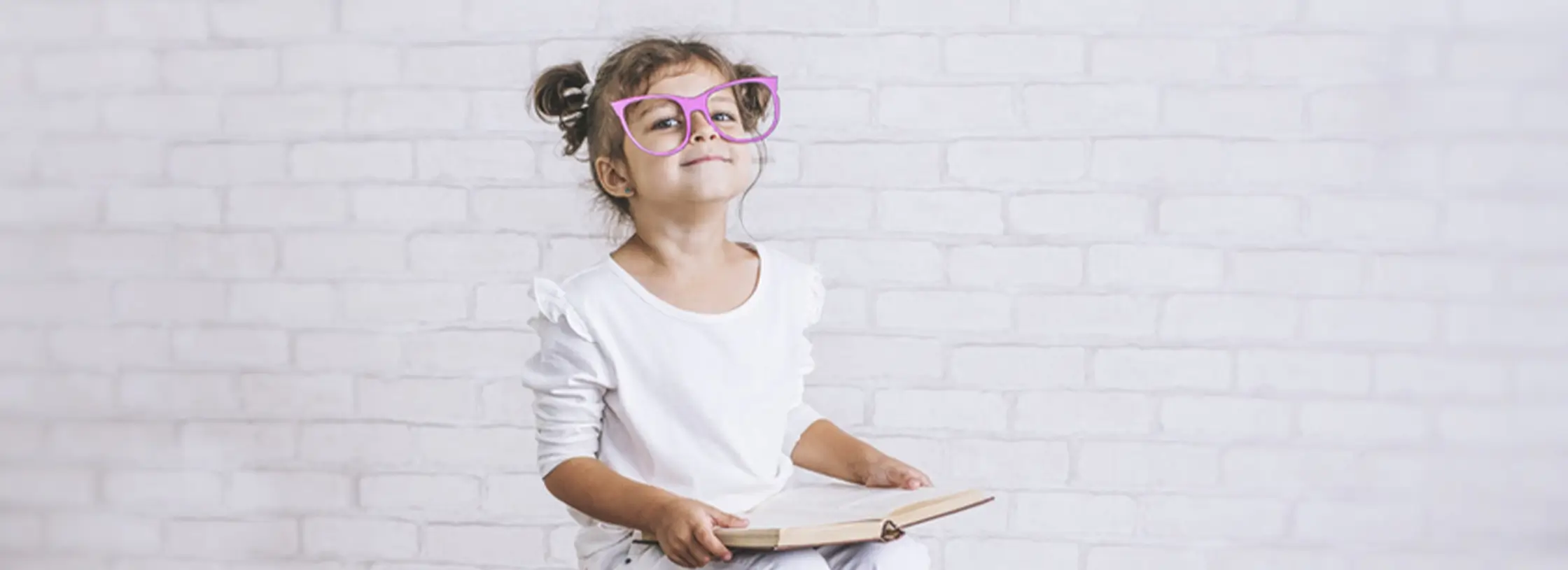 Mädchen mit Brille hält ein Buch in der Hand