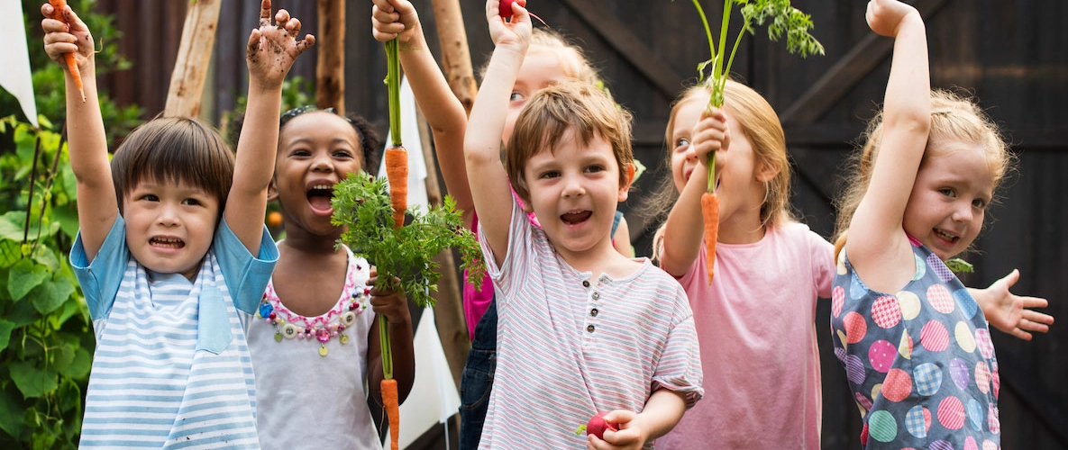 Kinder mit Karotten aus dem Garten in der Hand