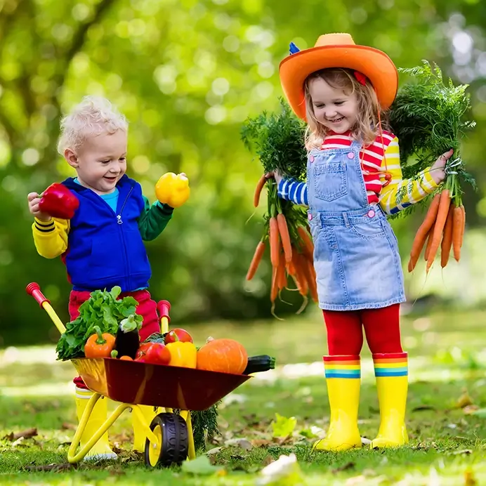 Kita-Projekte zum Thema Essen: Kinder beim gärtnern mit Schubkarre und Gemüse