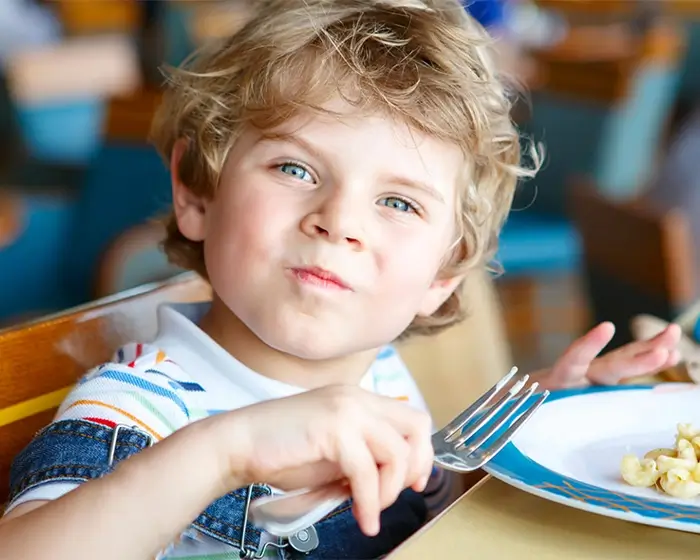 Gestaltung der Essenssituation in der Kita Junge am Essen mit einer Gabel