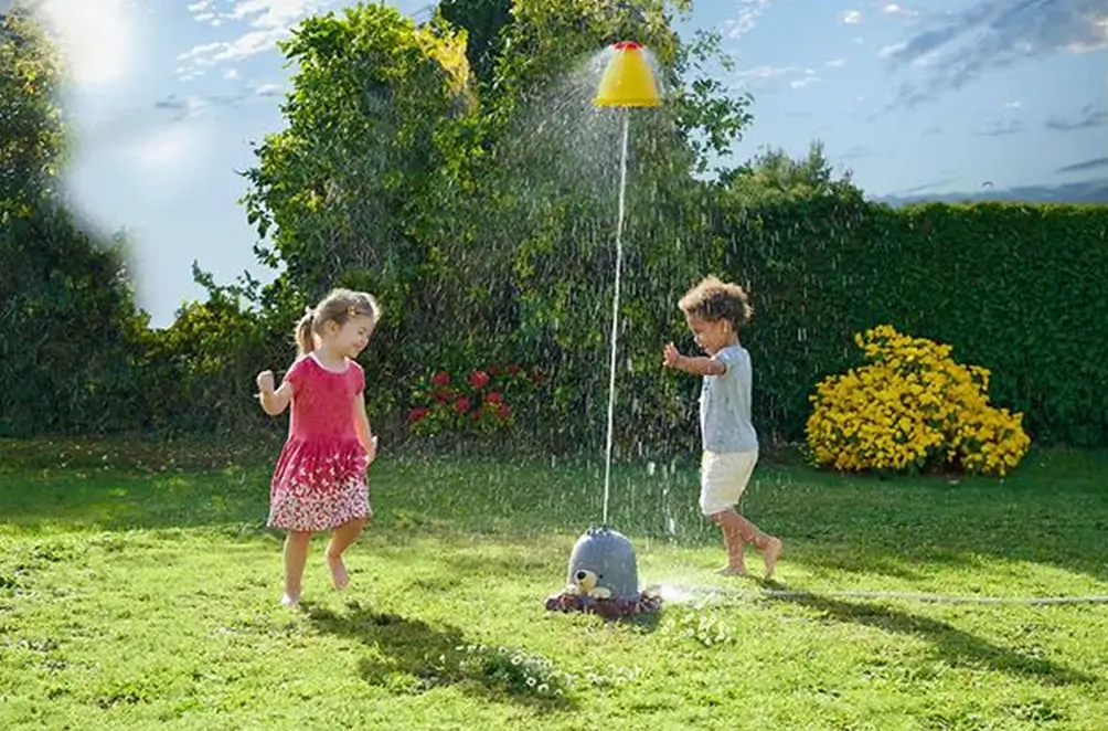 Kinder rennen um einen Wassersprinkler