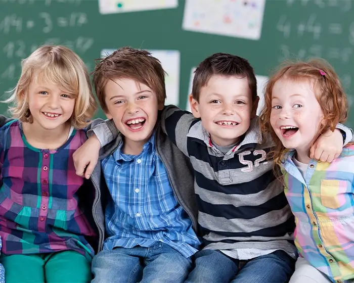 Vorschulerziehung in der Kita Kinder sitzen in einer Reihe vor einer Schultafel