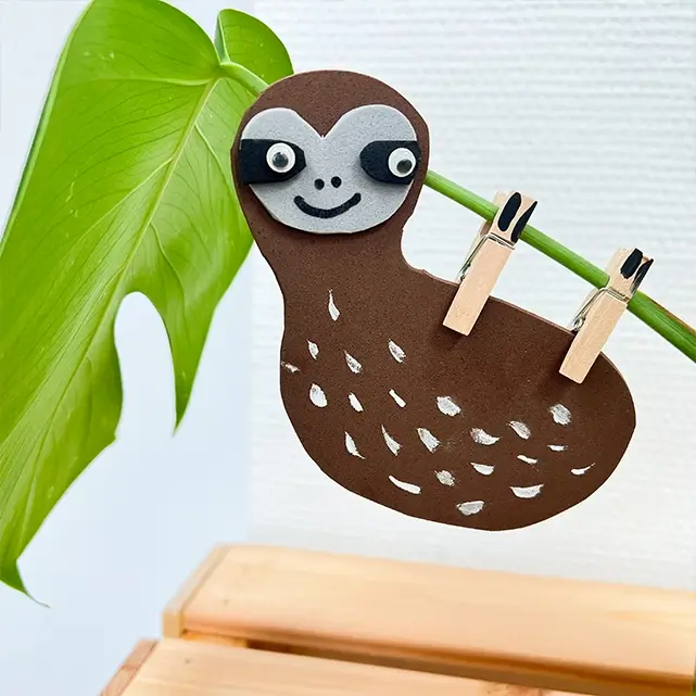 Selbst gebasteltes Faultier mit Wäscheklammern an einem Blatt