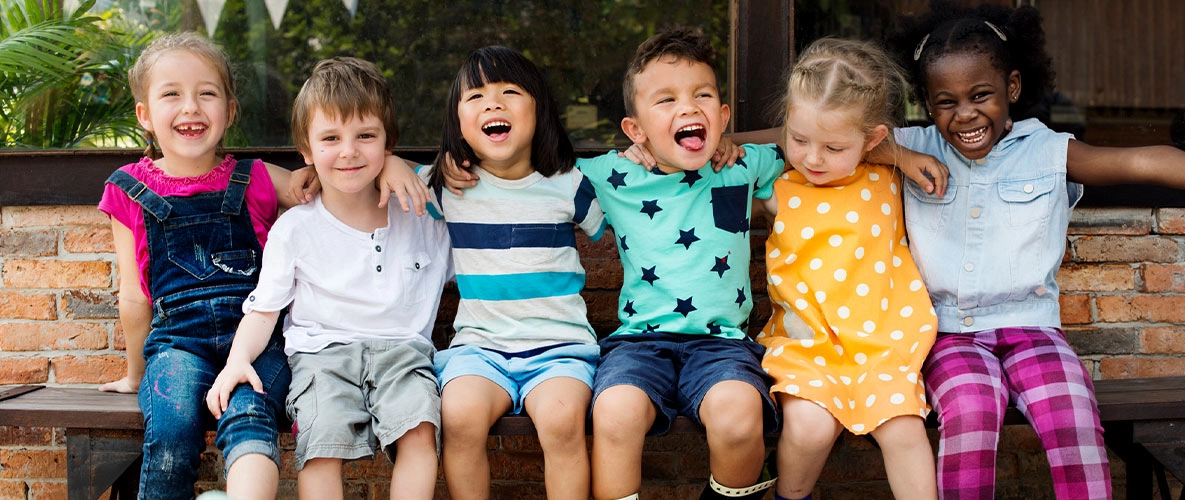sechs Kinder sitzen zusammen auf einer Bank